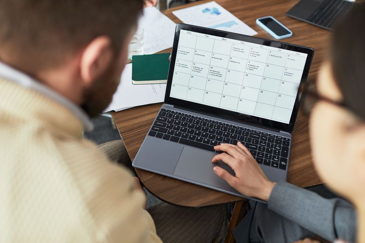 Équipe consultant un calendrier sur ordinateur portable